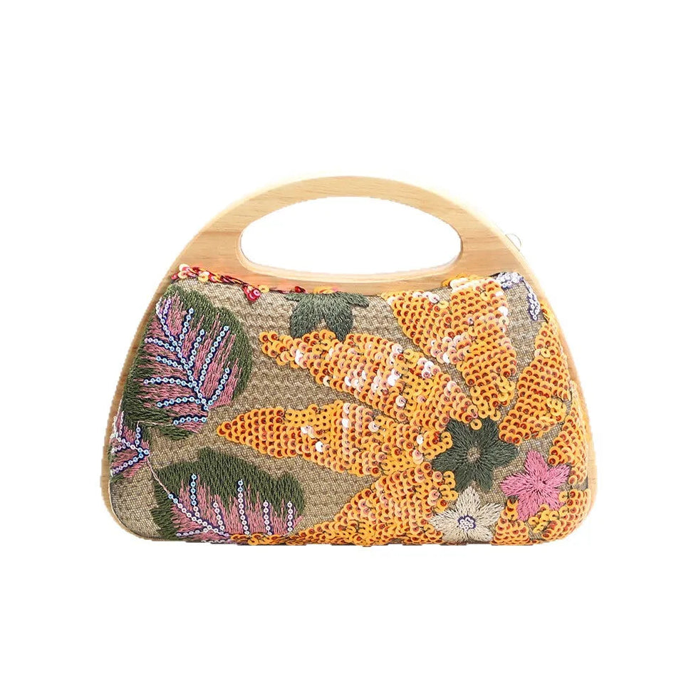 A small structured handbag with a curved light wood handle, featuring a textured beige body covered in orange, yellow, green, and pink floral and leaf beadwork, shown against a plain white background.